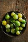 De cima de tomates de cereja verdes inteiros em boliche reunidos na fazenda durante a estação de colheita — Fotografia de Stock