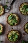 Top view of cauliflower and walnut cakes with greens near fork on planked wooden table — Stock Photo