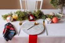 De cima configurações de mesa de Natal com uma decoração de grinalda, vermelho e branco, com talheres dourados e velas — Fotografia de Stock