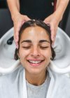 Ernte unkenntlich Master Waschen dunkler Haare einer Kundin mit geschlossenen Augen in Schönheitssalon — Stockfoto