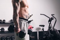 Seitenansicht der Ernte unkenntlich Bodybuilder mit Tätowierungen stehen mit schweren Hanteln während des Trainings im Fitnessstudio — Stockfoto