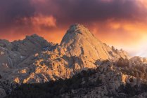 Rough stones covered with moss and bushes located on top of snowy mountain in Sierra de Guadarrama National Park in Madrid, Spain during sunset — Stock Photo