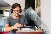 Uomo focalizzato in occhiali ascoltare musica in cuffie da giocatore in spazioso appartamento — Foto stock