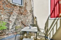 Scala con ringhiera in metallo decorato con pianta verde situato sulla terrazza con sedie a tavola vicino casa moderna con finestra — Foto stock