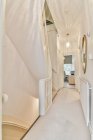 Лестница в узком коридоре с лампой и зеркалом, ведущая в спальню в солнечный день в уютной квартире — стоковое фото
