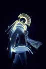 Vista lateral da pessoa irreconhecível em terno LED futurista de caráter espacial com luzes de néon brilhantes no fundo preto no estúdio — Fotografia de Stock