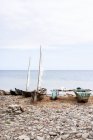 Alte Holzboote, die an der felsigen Küste in der Nähe des ruhigen Ozeans festmachen n So Tom und Prncipe unter wolkenverhangenem Himmel bei Tageslicht — Stockfoto