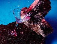 Сверху бокал алкогольного коктейля Blue Lagoon помещен на грубый камень в яркой студии — стоковое фото