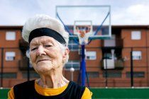Selbstbewusste reife Frau in Sportbekleidung mit durchbohrter Nase, die beim Training auf der Straße auf dem Sportplatz in die Kamera blickt — Stockfoto