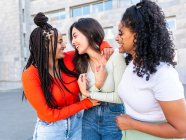 Cheerful multiracial women standing and laughing while spending time together on city street in daylight — Stock Photo