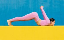 Seitenansicht der Ganzkörper-Barfußfrau, die sich in Variation der umgekehrten Heuschreckenpose mit erhobenen Armen und geraden Beinen dehnt — Stockfoto