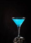 Blue Lagoon cocktail in crystal elegant glass placed on rough surface against black background — Stock Photo