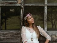 Hippie-Frau sitzt auf der Veranda ihrer Hütte und schaut weg — Stockfoto