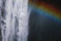 Paesaggio mozzafiato di arcobaleno che splende sulla rapida e potente cascata di Skogafoss che scorre attraverso la scogliera rocciosa in Islanda — Foto stock