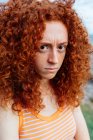 Mulher perturbada com cabelo encaracolado gengibre mostrando emoção de desagrado e olhando para a câmera — Fotografia de Stock