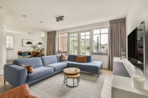 Sofá confortável e poltrona localizado perto da TV contra janelas e porta na sala de estar da propriedade moderna — Fotografia de Stock