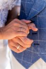 Cultiver couple marié sans visage dans des tenues de mariage tenant la main avec des alliances à la lumière du jour — Photo de stock