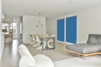 Design creativo degli interni della sala da pranzo con tavolo e sedie contro divano e poltrone su tappeto a casa — Foto stock
