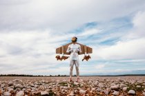 Maschio in abito argento e maschera scimmia in piedi con jetpack su terreno roccioso in estate — Foto stock