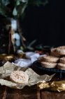 Pile of appetizing sweet shortbread cookies with hazelnuts served on plate on wooden table with festive wrapping paper and ribbons for Christmas celebration — Stock Photo