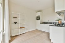 В светлой современной кухне новой квартиры расположены простые белые шкафы с гардеробами — стоковое фото