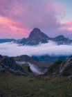 Niebla blanca gruesa flotando cerca de cresta de montaña rocosa áspera contra el cielo nublado en la naturaleza salvaje de España en la noche de verano - foto de stock