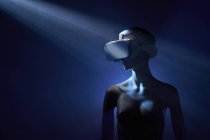 Manichino di donna con occhiali VR futuristici posto sotto proiezione luminosa in camera oscura — Foto stock