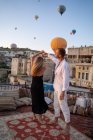 Full body of barefoot couple dancing together on rooftop terrace against hot air balloons flying in cloudless sky — Stock Photo
