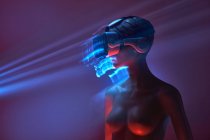 Manequim de mulher em óculos de realidade virtual futuristas colocados sob projeção brilhante na sala escura — Fotografia de Stock