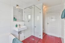 Diseño creativo del interior del cuarto de baño con ducha y lavabo debajo del espejo y la lámpara en casa - foto de stock