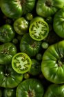 Top view of sliced of unripe berry of Solanum lycopersicum plant with scattered tomatoes — Stock Photo