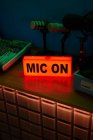 Современный микрофон на штативе помещен на стол в темной студии с неоновой подсветкой перед записью подкаста — стоковое фото