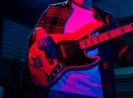 Crop анонімний чоловічий гітарист, який грає на електрогітарі в клубі з неоновим фіолетовим і синім світлом — стокове фото