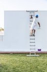 Неузнаваемый молодой художник рисует фасад квартиры роликом с лестницы — стоковое фото