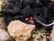 D'en haut du charbon de bois brûlant et de la torche avec des étincelles orange entourées de pierres brutes au camping — Photo de stock