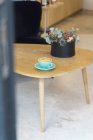 Горщик гарячої кави з креативним мистецтвом латте, що подається на тарілці з чайною ложкою на дерев'яному столі в сучасному легкому кав'ярні — стокове фото