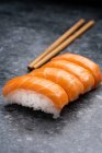 Set ähnlich schmackhaftes traditionelles japanisches Sushi mit weißem Reis und frischem Lachs, serviert auf einem Marmortisch neben Holzstäbchen im hellen Raum — Stockfoto