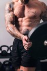 Урожай невпізнаваний спортсмен з м'язистим тілом і голий торс, що стоїть з важкою вагою тарілки в спортзалі — стокове фото