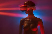 Dummy of woman in futuristic VR goggles placed under bright projection in dim room — Stock Photo