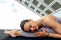 Peaceful female with closed eyes practicing front splits forward bend asana on street with solar panel in city — Stock Photo