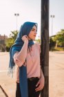 Seitenansicht positiver muslimischer Frauen mit traditionellem Kopftuch und Wegschauen an sonnigen Tagen in der Stadt — Stockfoto
