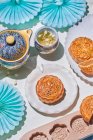 D'en haut de mooncakes traditionnels avec remplissage servi sur la table avec des moules de cuisson près de la bouilloire avec tisane dans la pièce lumineuse — Photo de stock