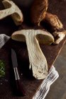 Vista superior do corte cru Boletus edulis cogumelos na tábua de corte de madeira com alho e salsa na cozinha leve durante o processo de cozimento — Fotografia de Stock