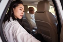 Vista lateral do passageiro feminino asiático sentado no carro e porta de fechamento da cabine — Fotografia de Stock