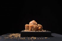 Gourmet pasta de membrillo jalea en placa de cerámica espolvoreada con semillas de sésamo sobre fondo negro - foto de stock