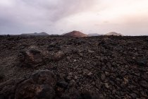 Ruta áspera entre lava oscura contra el volcán Bermeja en Yaiza, Lanzarote, Islas Canarias en España - foto de stock