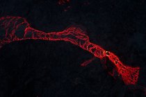 Draufsicht auf glühend rotes Magma, das nachts im Hochland Islands in Dunkelheit auf dunkler bergiger Oberfläche fließt — Stockfoto
