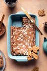 Top view of tasty baked brownie with almond flakes in baking tray with cookies placed on table with cocoa powder — Stock Photo
