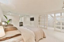 Bett mit Kissen und Bettdecke gegen Türen und Fernseher mit schwarzem Bildschirm im Leuchtturm — Stockfoto