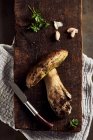 Vue de dessus des champignons Boletus edulis coupés crus sur planche à découper en bois avec ail et persil dans la cuisine légère pendant le processus de cuisson — Photo de stock